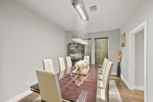 dining space featuring wood finished floors, visible vents, and baseboards