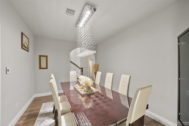 dining room with baseboards, visible vents, stairway, wood finished floors, and an inviting chandelier