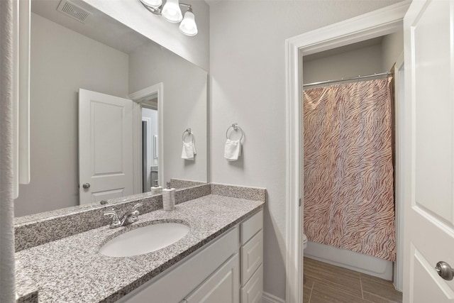 full bathroom with toilet, vanity, visible vents, and baseboards