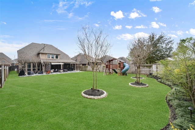 view of yard featuring a patio area, a playground, and a fenced backyard