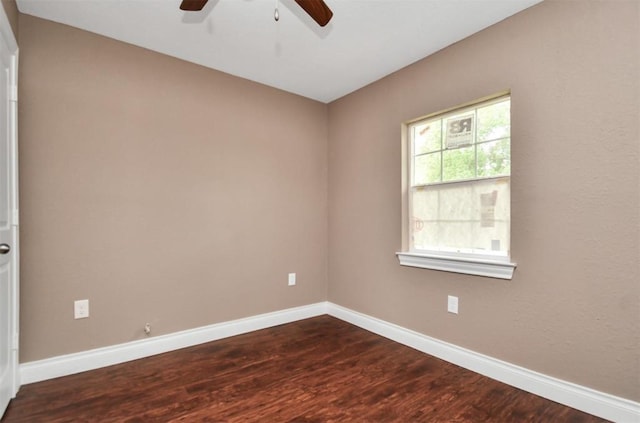 spare room with ceiling fan, baseboards, and dark wood-type flooring