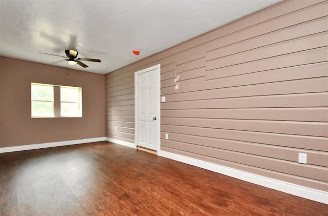 spare room with ceiling fan, dark wood-style flooring, and baseboards