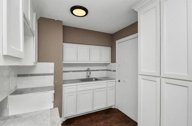 kitchen featuring dark wood-style floors, white cabinets, a sink, and light countertops