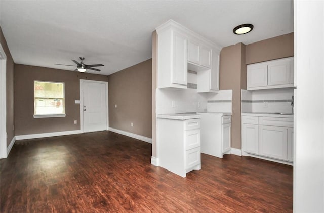 kitchen with dark wood-style flooring, open floor plan, white cabinets, ceiling fan, and baseboards