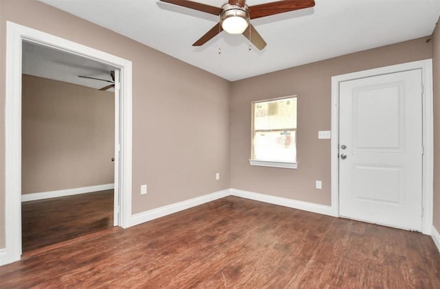 interior space featuring a ceiling fan, dark wood finished floors, and baseboards