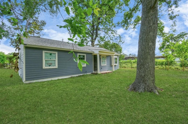 back of house featuring fence and a lawn