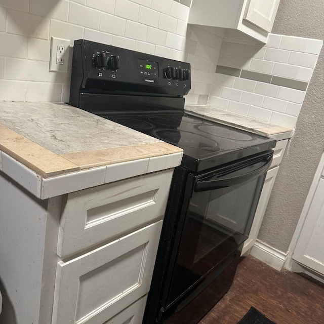 kitchen with electric range, tasteful backsplash, dark wood-style flooring, and light countertops