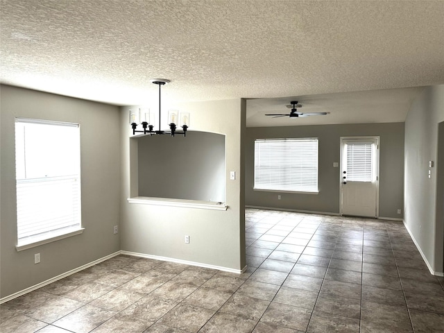 unfurnished dining area featuring a wealth of natural light, baseboards, and ceiling fan with notable chandelier