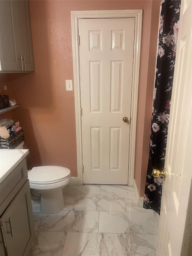 full bath with baseboards, marble finish floor, vanity, and toilet
