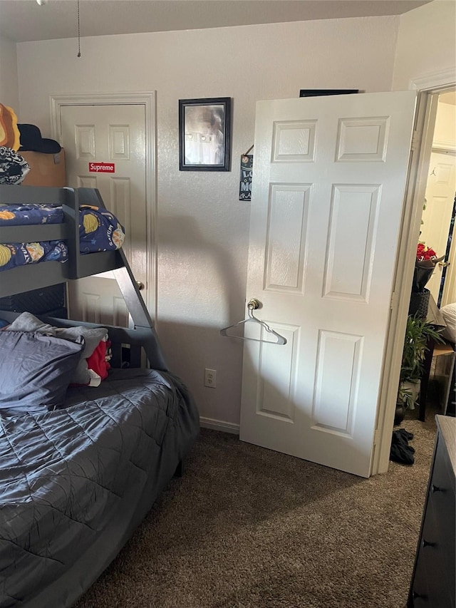 bedroom featuring dark carpet and baseboards