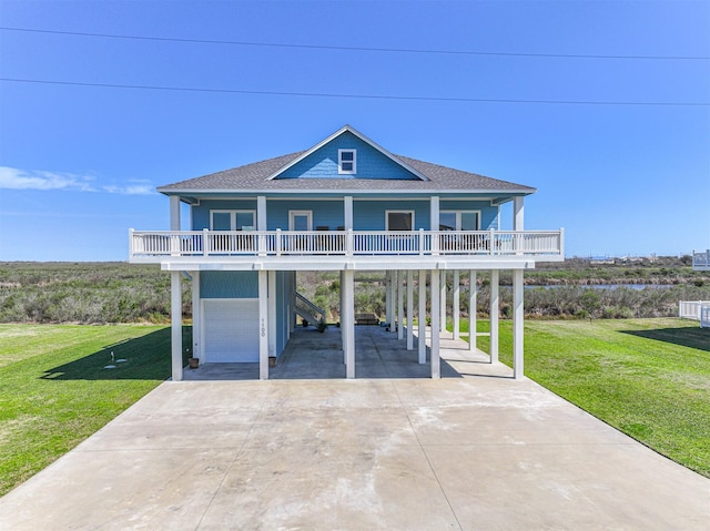 coastal inspired home with a carport, a porch, roof with shingles, and a front yard