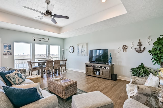 living room featuring baseboards, a raised ceiling, and wood finished floors