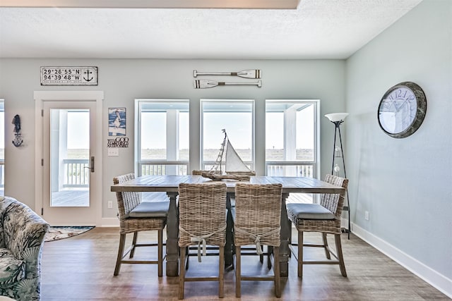 dining area featuring a textured ceiling, baseboards, and wood finished floors