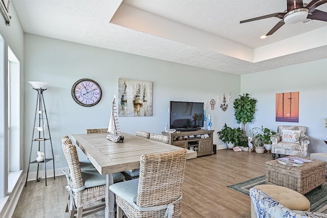 dining room with light wood-style floors, a textured ceiling, and baseboards