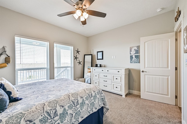 bedroom with a ceiling fan, light carpet, and baseboards