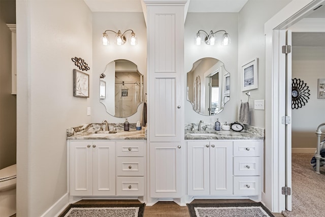 bathroom with double vanity, a sink, toilet, and a shower stall