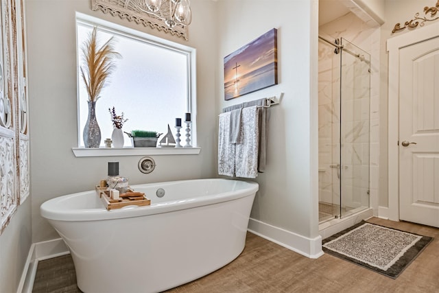 bathroom featuring a freestanding tub, a shower stall, baseboards, and wood finished floors