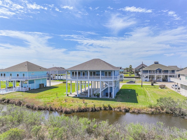 rear view of house with a residential view, a water view, a yard, and stairs