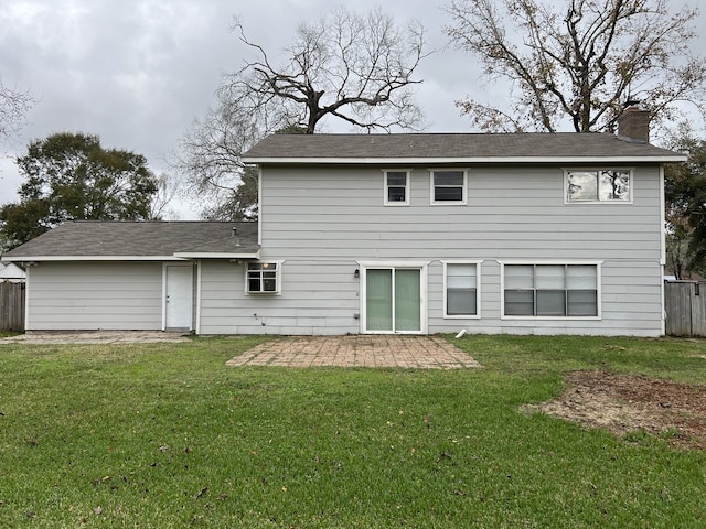 back of property featuring a chimney, a patio, fence, and a lawn