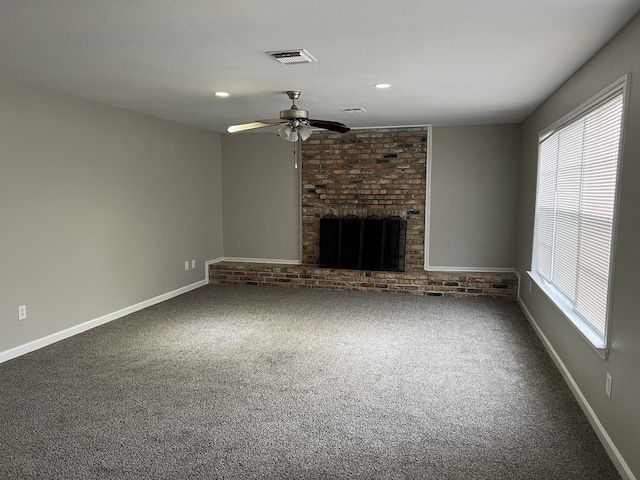 unfurnished living room with carpet, visible vents, a brick fireplace, ceiling fan, and baseboards