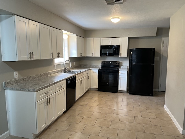 kitchen featuring black appliances, baseboards, white cabinetry, and a sink