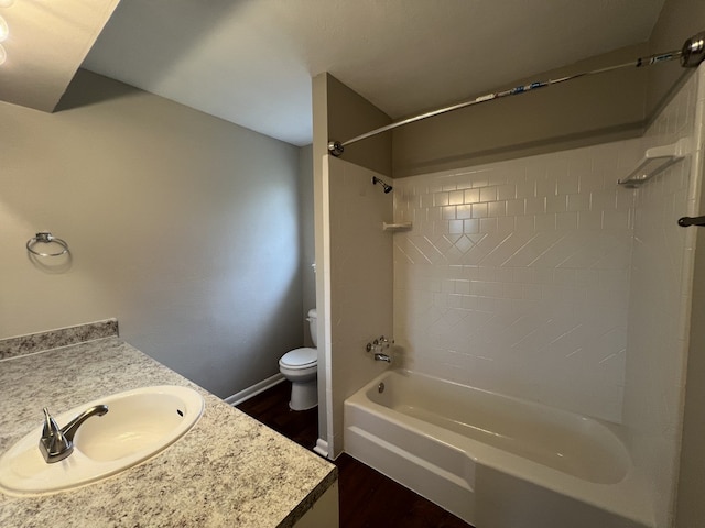 full bath featuring baseboards, toilet, wood finished floors, vanity, and washtub / shower combination