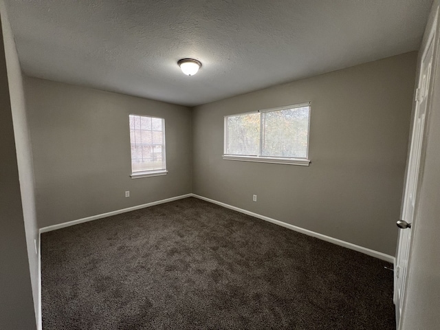 unfurnished room featuring dark colored carpet, a textured ceiling, and baseboards