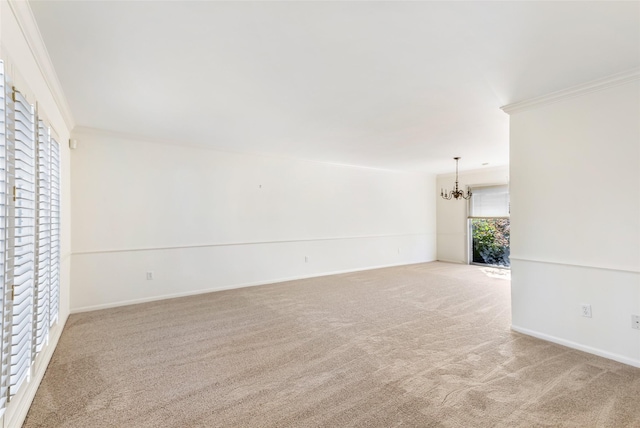 unfurnished room featuring a chandelier, carpet flooring, ornamental molding, and baseboards