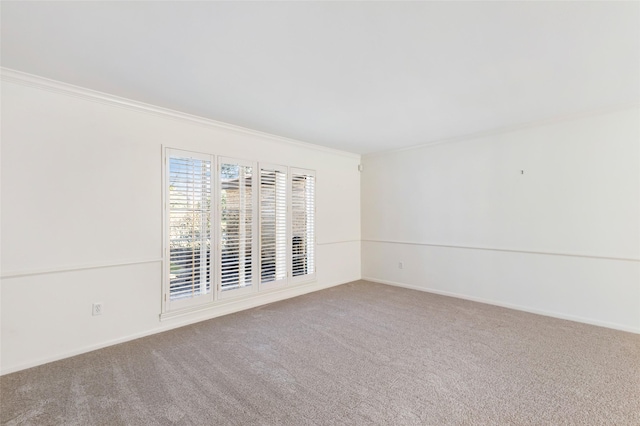 carpeted spare room featuring ornamental molding and baseboards