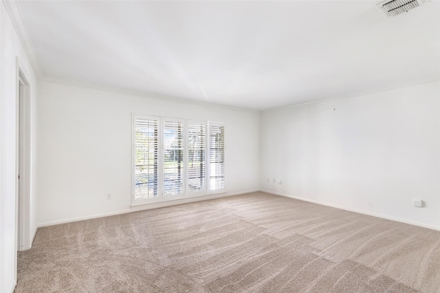 spare room featuring carpet floors, ornamental molding, visible vents, and baseboards