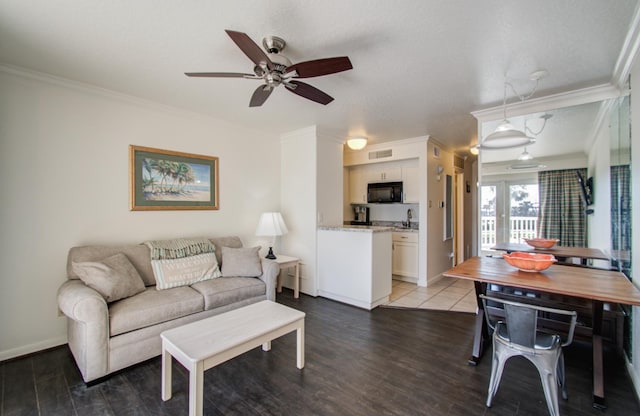 living area featuring visible vents, baseboards, a ceiling fan, wood finished floors, and crown molding