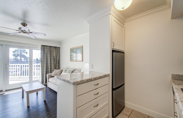 kitchen featuring ornamental molding, freestanding refrigerator, white cabinets, and a textured ceiling