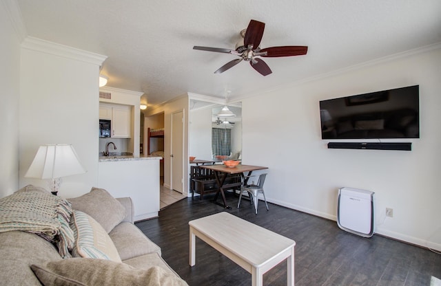 living area with ceiling fan, ornamental molding, dark wood-type flooring, and baseboards