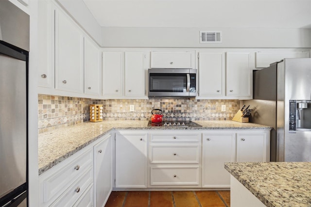 kitchen featuring white cabinets, stainless steel appliances, visible vents, and decorative backsplash