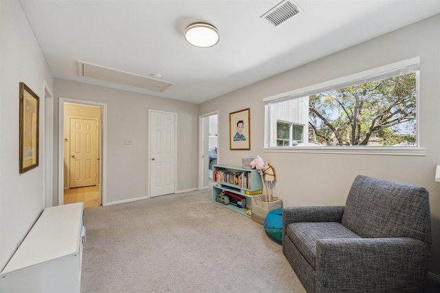 sitting room featuring attic access, visible vents, light carpet, and baseboards