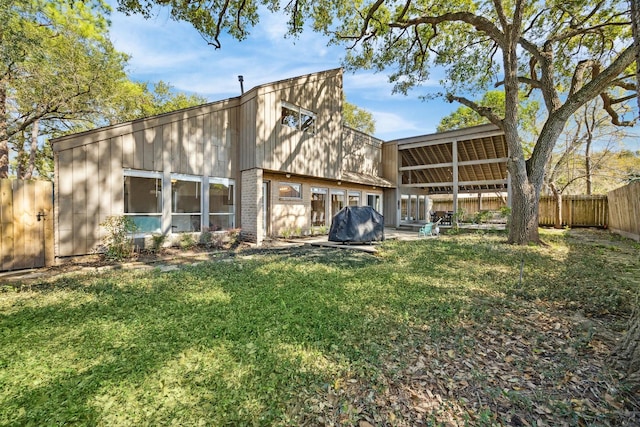 back of house featuring a lawn and fence