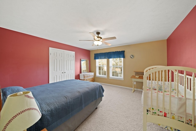 carpeted bedroom featuring a closet, baseboards, and a ceiling fan