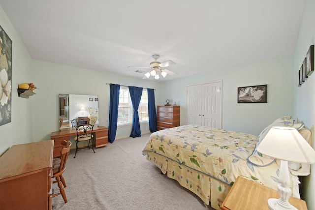 bedroom featuring light carpet, ceiling fan, baseboards, and a closet