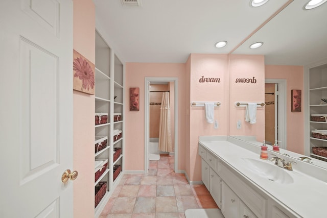 bathroom with vanity, a spacious closet, recessed lighting, and baseboards