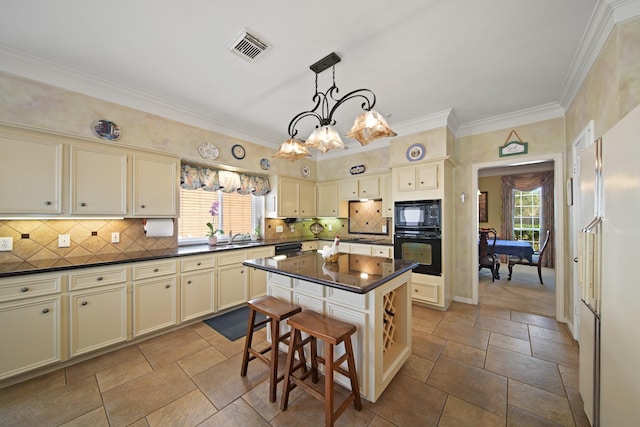 kitchen featuring dark countertops, visible vents, tasteful backsplash, cream cabinets, and black appliances