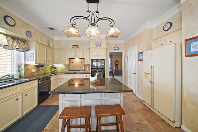 kitchen featuring visible vents, black appliances, a sink, cream cabinets, and backsplash