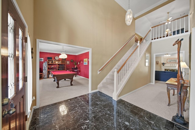 carpeted foyer with stairway, a high ceiling, marble finish floor, and ornamental molding