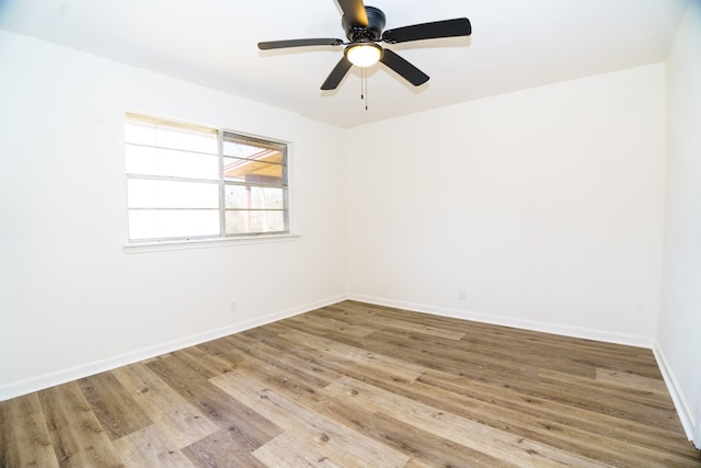 spare room with wood finished floors, a ceiling fan, and baseboards