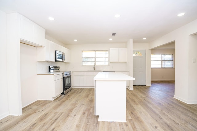 kitchen with a healthy amount of sunlight, a kitchen island, appliances with stainless steel finishes, and light countertops