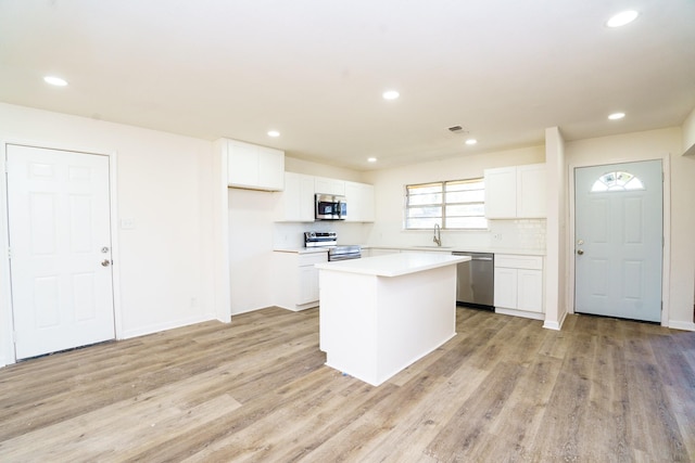 kitchen featuring appliances with stainless steel finishes, white cabinets, a sink, and a kitchen island