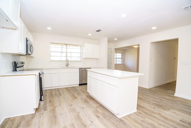 kitchen with stainless steel appliances, light countertops, a sink, and light wood-style flooring