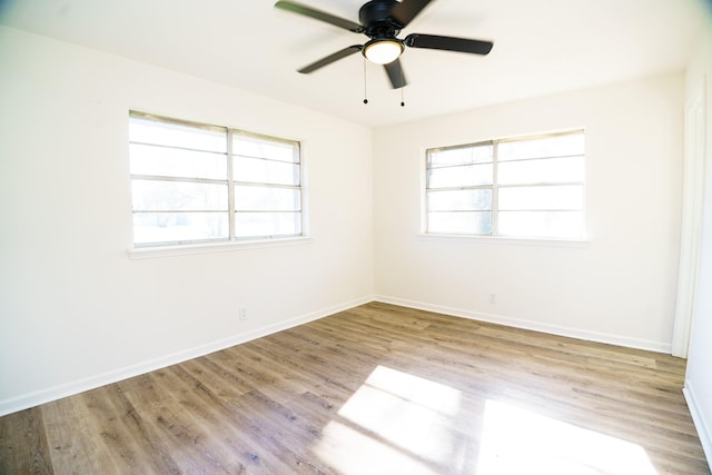 empty room featuring plenty of natural light, wood finished floors, and baseboards