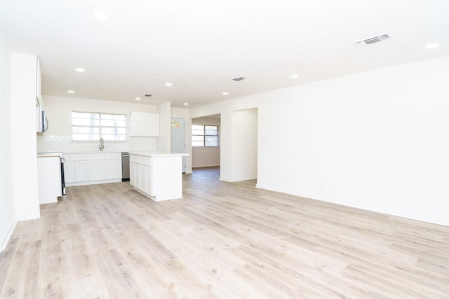 interior space with baseboards, visible vents, light wood-style flooring, a sink, and recessed lighting