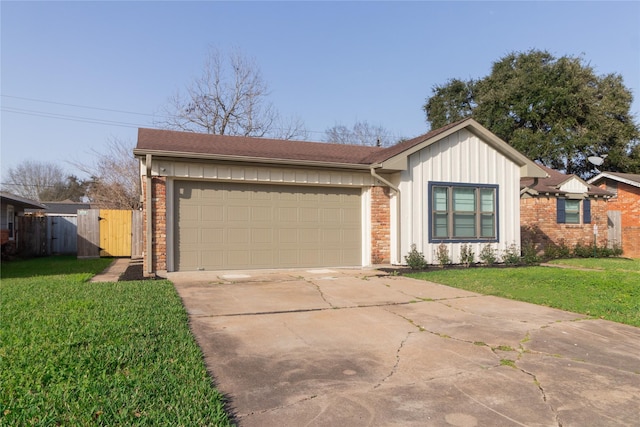 view of front of home with board and batten siding, a front yard, concrete driveway, and a gate