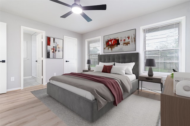 bedroom featuring light wood finished floors, connected bathroom, a ceiling fan, and baseboards